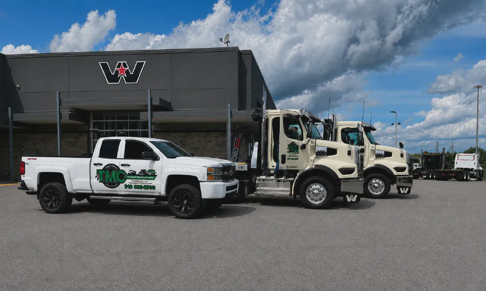 La flotte TMC : la camionnette Silverado et les deux dépanneuses Western Star, devant le concessionnaire
